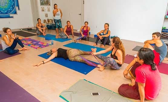 Group seated in a circle on mats watching a teacher demonstrate