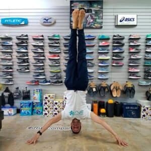 Hector Arana in a headstand on the floor of his running shop